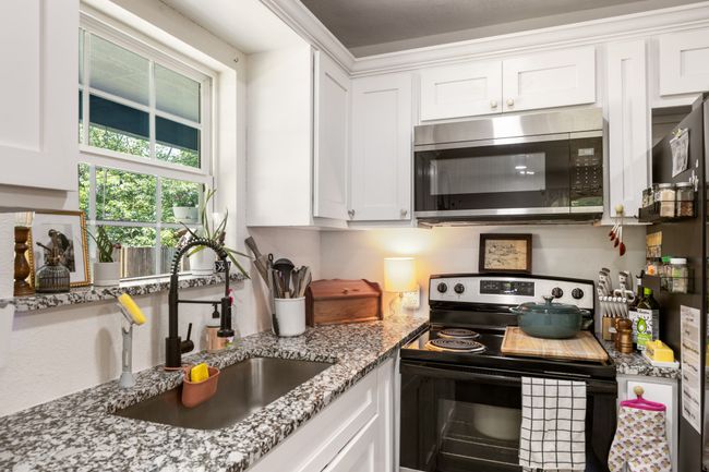 Kitchen featuring appliances with stainless steel finishes, white cabinets, and light stone counters | Image 8
