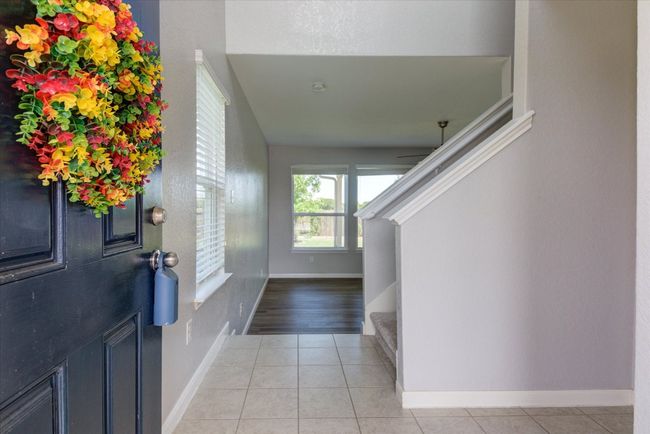 Welcoming foyer featuring a graceful staircase and light, patterned tile flooring that brightens the space. | Image 4