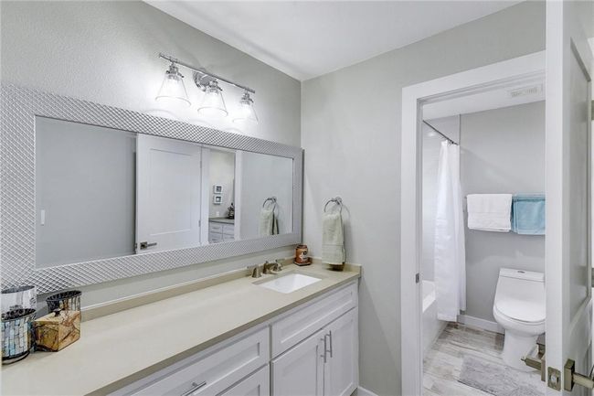 Bathroom with vanity, toilet, baseboards, shower / tub combo with curtain, and wood finished floors | Image 15