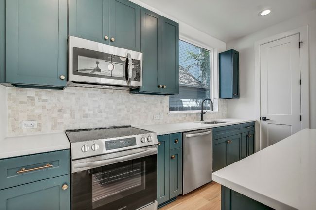Kitchen featuring stainless steel appliances, a sink, light wood-type flooring, light countertops, and decorative backsplash | Image 5
