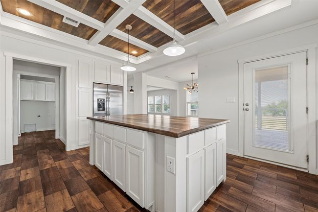 Kitchen featuring butcher block counters, a wood ceiling with exposed beams, hanging light fixtures, white cabinetry, and coffered ceiling | Image 12