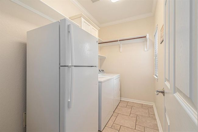 An oversized utility room has ample storage for additional appliances, shelves and rods for storage and hanging! A small window allows in great natural light! | Image 15