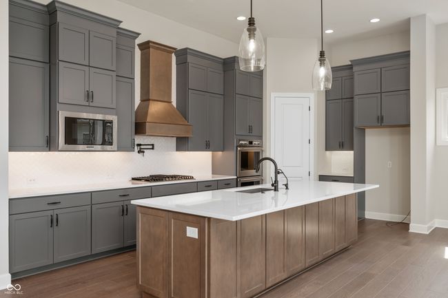 Kitchen featuring stainless steel appliances, backsplash, dark wood-style flooring, and custom range hood. | Image 6