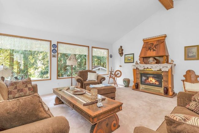Living room featuring beam ceiling, high vaulted ceiling, a glass covered fireplace, and light carpet | Image 11