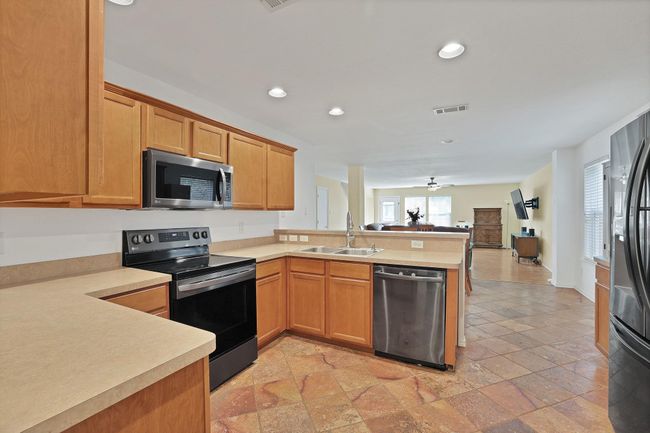 Kitchen featuring appliances with stainless steel finishes, a peninsula, recessed lighting, light countertops, and open floor plan | Image 10