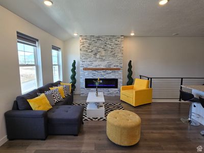 Living room with a stone fireplace, a textured ceiling, and dark hardwood / wood-style floors | Image 2