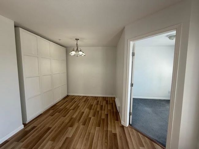Unfurnished dining area featuring a notable chandelier, dark wood-style flooring, and baseboards | Image 5