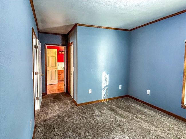 Unfurnished bedroom featuring ornamental molding, dark colored carpet, and baseboards | Image 16