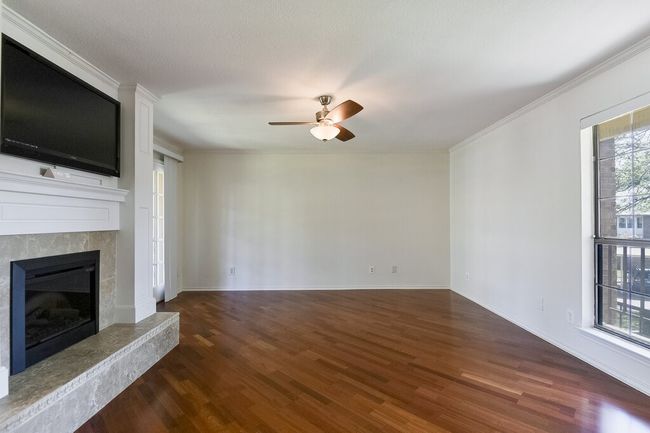 Unfurnished living room featuring a tile fireplace, a ceiling fan, ornamental molding, and wood finished floors | Image 4