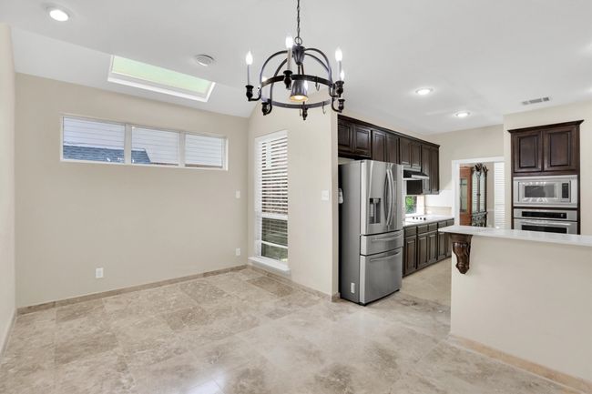 Kitchen featuring dark brown cabinets, visible vents, a skylight, light countertops, and appliances with stainless steel finishes | Image 12