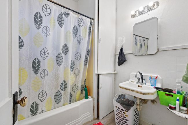 Full bathroom with tile walls, shower / tub combo with curtain, and wood finished floors | Image 10