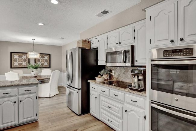 Kitchen featuring white cabinets, appliances with stainless steel finishes, pendant lighting, and light wood-type flooring | Image 15