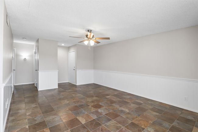 Unfurnished room featuring a ceiling fan, wainscoting, a textured ceiling, and stone finish floor | Image 19