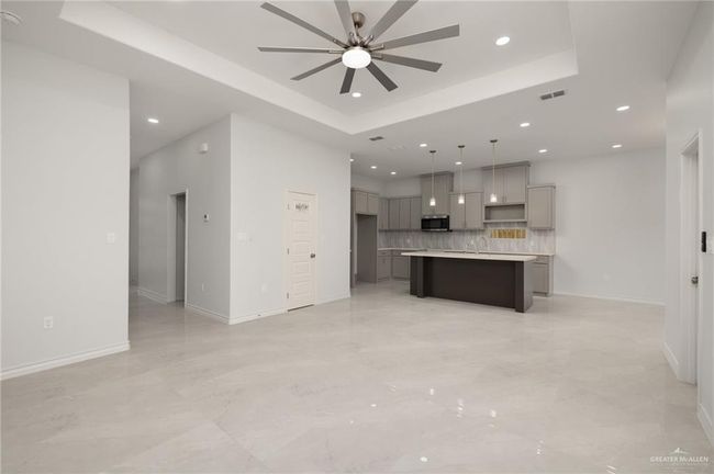 Unfurnished living room featuring recessed lighting, ceiling fan, a raised ceiling, and light marble finish flooring | Image 4