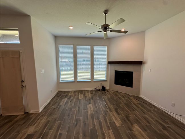 Unfurnished living room with dark wood finished floors, baseboards, and a ceiling fan | Image 7