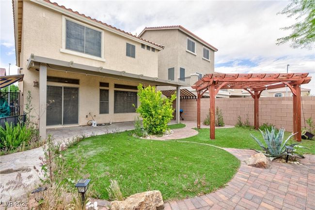 Rear view of property with a fenced backyard, a pergola, a patio area, a yard, and stucco siding | Image 5