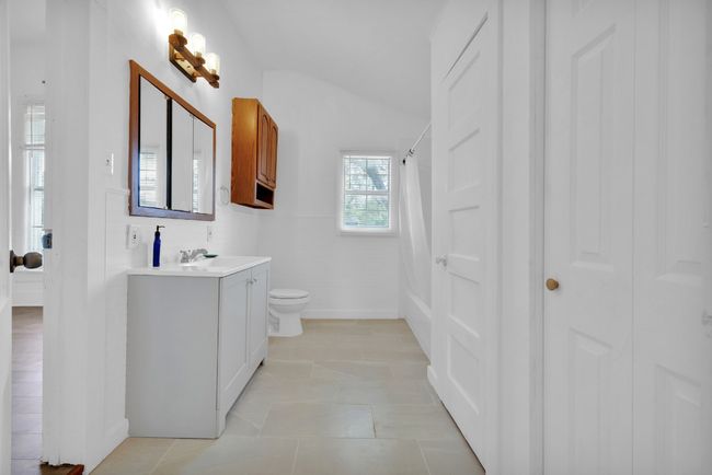 Bathroom with vaulted ceiling, tile patterned floors, vanity, toilet, and a shower with shower curtain | Image 15