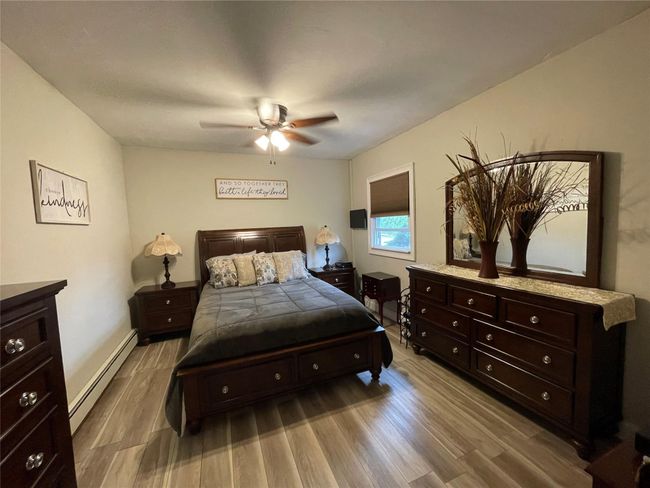 Bedroom with baseboard heating, wood finished floors, a ceiling fan, and baseboards | Image 21