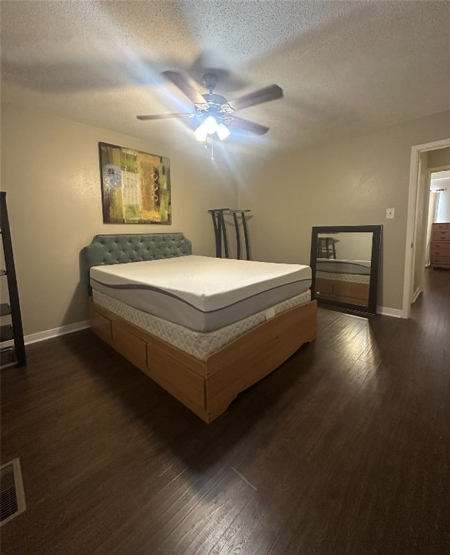 Bedroom with baseboards, dark wood finished floors, a textured ceiling, and a ceiling fan | Image 20