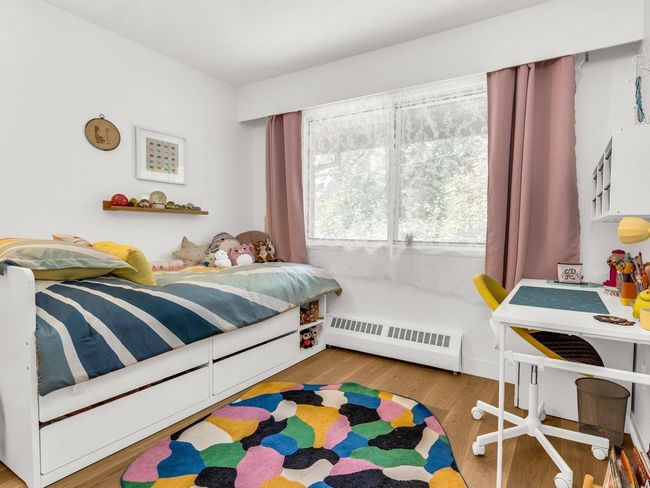 Bedroom featuring a baseboard heating unit and wood finished floors | Image 18