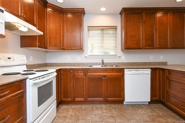 Kitchen with white appliances, a sink, under cabinet range hood, a peninsula, and recessed lighting | Image 4