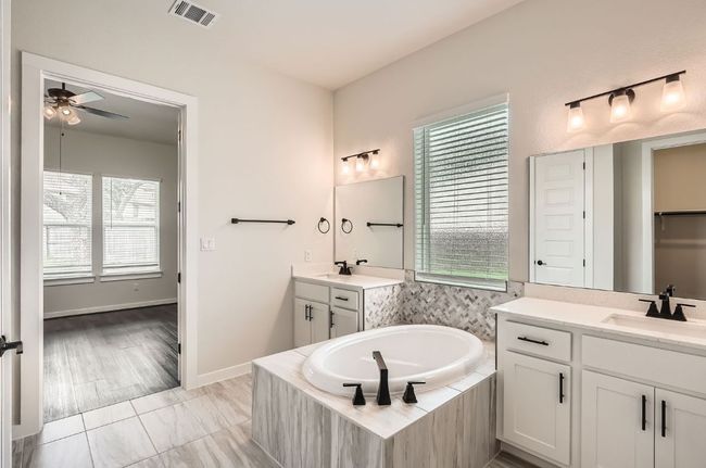 Bathroom with a ceiling fan, plenty of natural light, a garden tub, and two vanities | Image 16