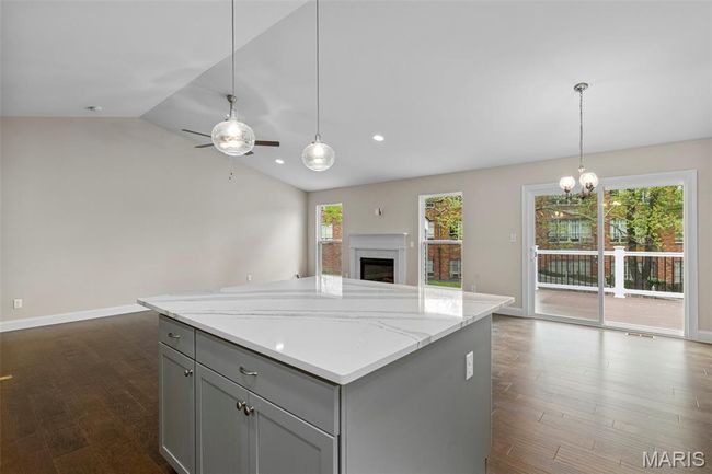 Kitchen featuring open floor plan, gray cabinetry, vaulted ceiling, dark wood finished floors, and a kitchen island | Image 10