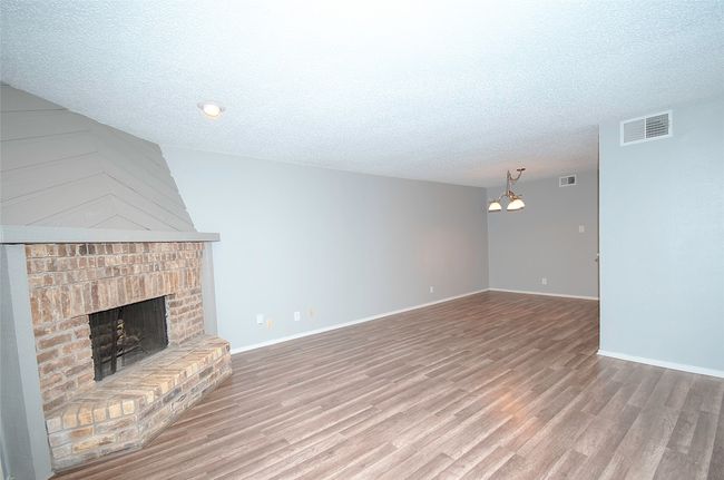 Unfurnished living room featuring a fireplace, hardwood / wood-style flooring, a chandelier, and a textured ceiling | Image 14