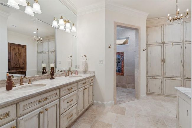 The Primary Ensuite Bath is your own personal spa! The custom-designed and faux-finished cabinetry boasts double sinks, alaundry chute, and a wall of cabinets designed to store towels, linens, and more. The sparklingmirrors hide specialized cabinets byRobern, which are lighted and electrified inside. | Image 23