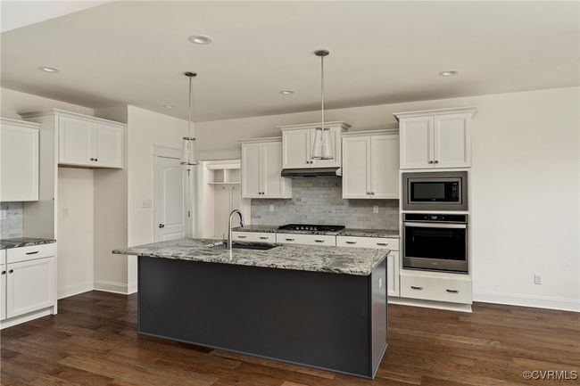 Kitchen with appliances with stainless steel finishes, backsplash, white cabinets, dark wood-type flooring, and recessed lighting | Image 10