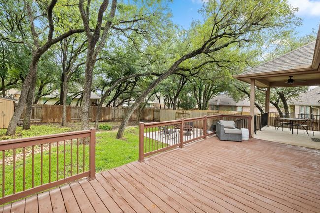 Wooden deck with a fenced backyard, ceiling fan, and outdoor dining space | Image 32