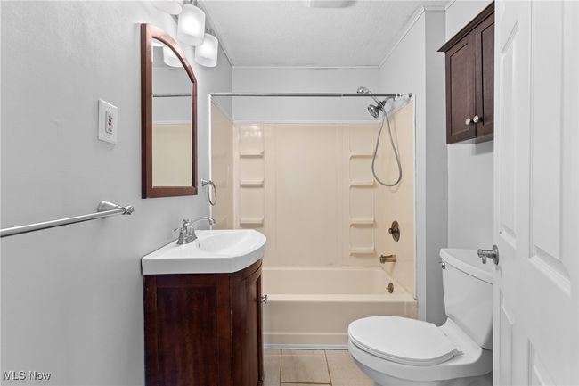 Bathroom featuring vanity, shower / bath combination, toilet, a textured ceiling, and tile patterned floors | Image 15