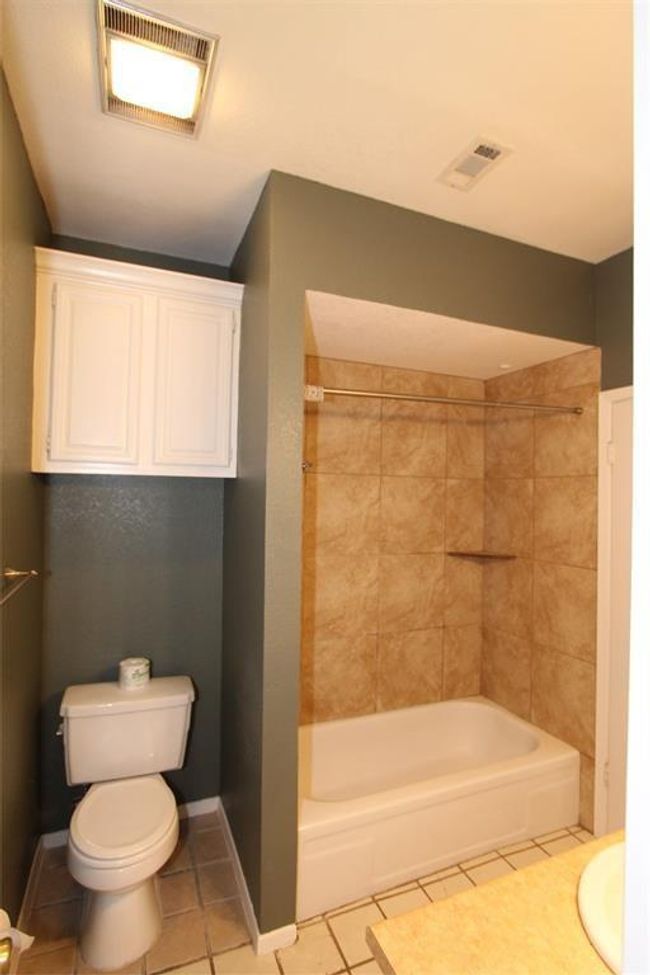 Full bath featuring toilet, tile patterned flooring, shower / tub combination, and baseboards | Image 7