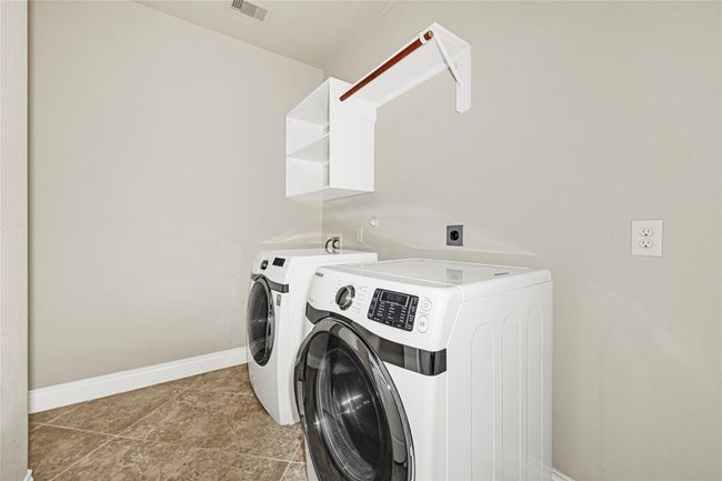 A laundry room with built-in shelving offers practical storage and ample space for household tasks. | Image 22