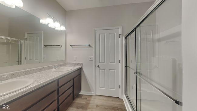 bathroom featuring a stall shower, wood finished floors, double vanity, and a sink | Image 10
