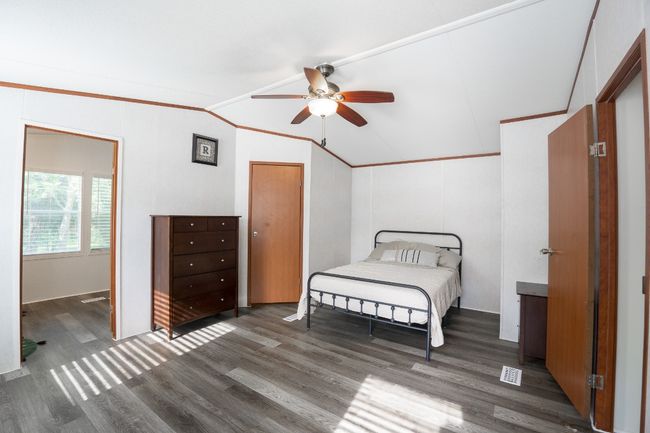 Bedroom featuring lofted ceiling, wood finished floors, ornamental molding, and a ceiling fan | Image 15