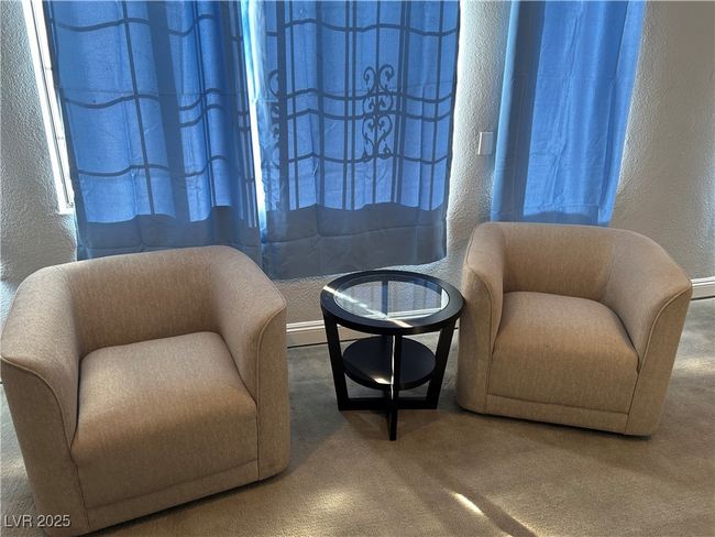 Living area with a textured wall and carpet flooring | Image 13