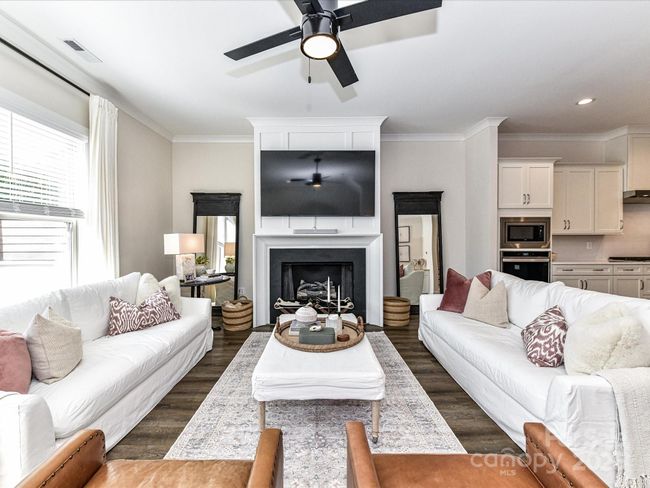 Great Room offers crown molding, cozy fireplace with gas logs, ceiling fan/light, deck access & LVP floors! | Image 16