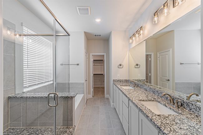 Full bathroom with double vanity, a shower stall, tile patterned flooring, a walk in closet, and a bath | Image 24