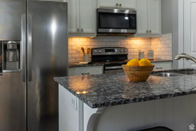 Kitchen with stainless steel appliances, a sink, dark stone countertops, and backsplash | Image 6