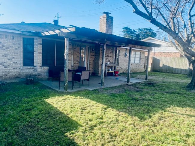 Back of property featuring brick siding, a chimney, a lawn, a patio area, and fence | Image 17