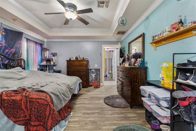 Bedroom with ceiling fan, ornamental molding, a tray ceiling, and light hardwood / wood-style floors | Image 15