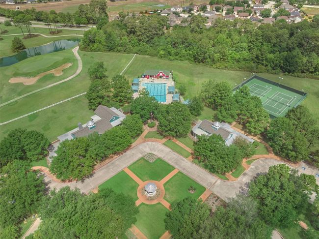 This aerial photo showcases the central swimming pool, tennis/pickleball courts, and lush green surroundings. It features well-maintained pathways, a gazebo, and nearby golf course views, offering a serene and recreational lifestyle. | Image 36