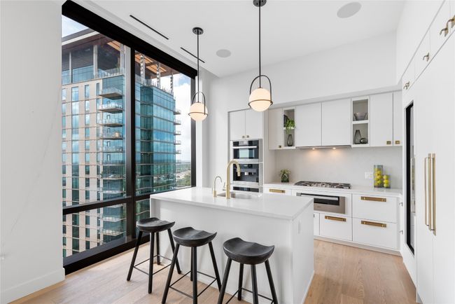Kitchen featuring modern cabinets, a sink, healthy amount of natural light, light wood-style floors, and expansive windows | Image 4