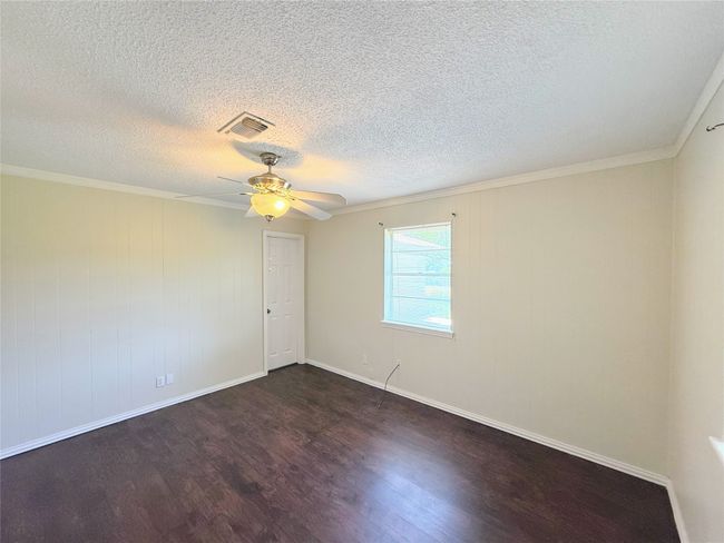 Unfurnished room featuring dark wood-style flooring, ceiling fan, a textured ceiling, and ornamental molding | Image 11