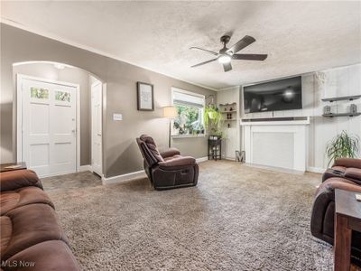 Carpeted living room with a textured ceiling and ceiling fan | Image 2