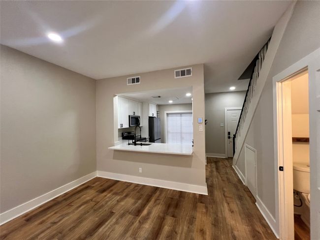 Unfurnished living room with a sink, dark wood-style flooring, baseboards, and recessed lighting | Image 10