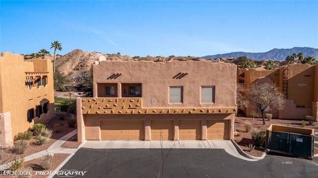 Pueblo-style home featuring an attached garage, aphalt driveway, and a mountain view | Image 56