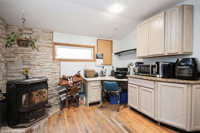 Office with built in desk, lofted ceiling, a wood stove, and light wood-type flooring | Image 9