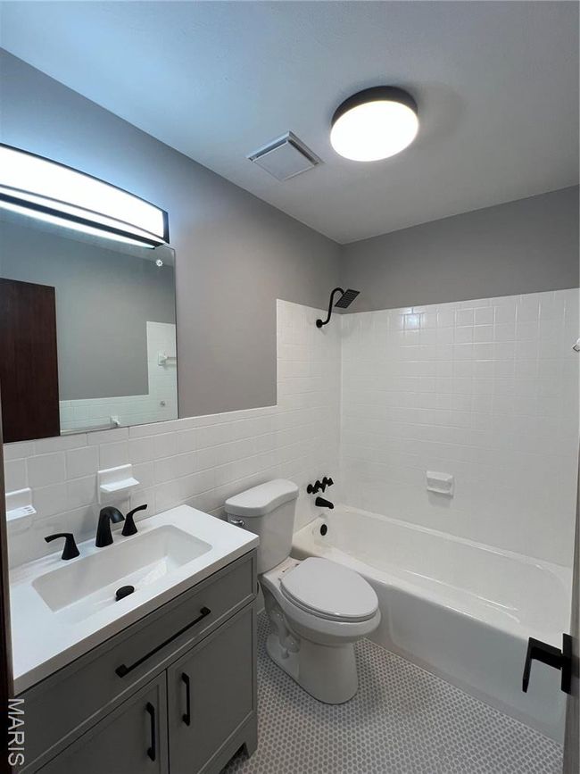 Full bath with tile walls, toilet, vanity, visible vents, and shower combination | Image 13